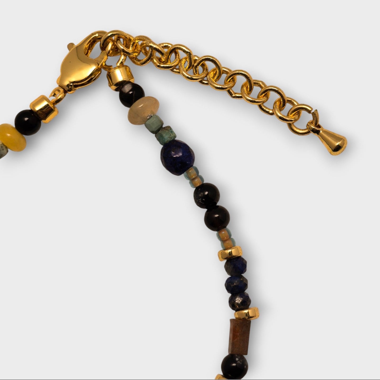 Bracelet with gold chain and multicolored beads on a white background